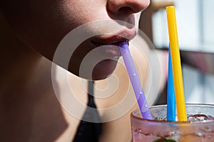 Closeup of womans lips drinking with pink straw. Woman drink cocktail. Close up wet sexy lips.