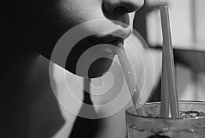 Closeup of womans lips drinking with pink straw. Woman drink cocktail. Close up wet sexy lips.