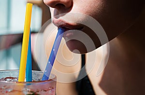 Closeup of womans lips drinking with pink straw. Woman drink cocktail. Close up wet sexy lips.