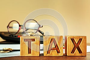 Closeup of wooden blocks with word TAX on table closeup