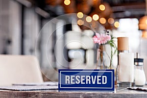Detailné drevený modrý biely obdĺžnikový doska slovo rezervované stojace na šedá starodávny stôl v reštaurácia najbližšie na nastavenie 