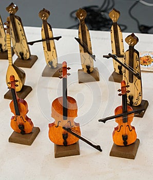 Closeup of wooden cello miniatures on the table with other musical instruments on the background