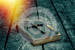 Closeup of wooden Christian cross on bible on the old table.