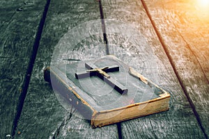 Closeup of wooden Christian cross on bible on the old table.