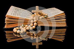 Closeup of wooden Christian cross on bible and prayer beads on black.Church utensils