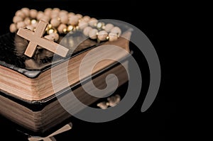 Closeup of wooden Christian cross on bible and prayer beads, Church utensils