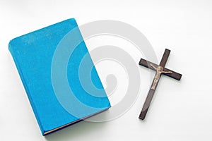 Closeup of wooden christian cross and bible on the white background.