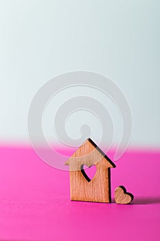 Closeup wooden house with hole in form of heart on vibrant two-colored background