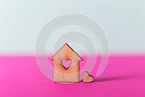 Closeup wooden house with hole in form of heart on vibrant two-colored background