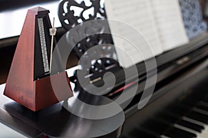 Closeup of wooden metronome on an old black piano