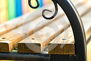 Closeup of wooden park bench with metal handgrip outdoors