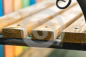 Closeup of wooden park bench with metal handgrip outdoors