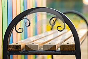 Closeup of wooden park bench with metal handgrip outdoors