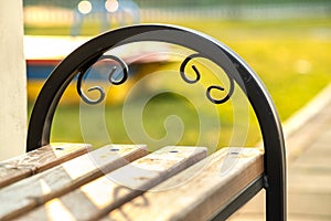 Closeup of wooden park bench with metal handgrip outdoors