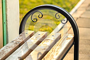 Closeup of wooden park bench with metal handgrip outdoors