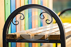 Closeup of wooden park bench with metal handgrip outdoors