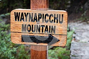 Closeup of wooden pointing sign to Waynapicchu mountain