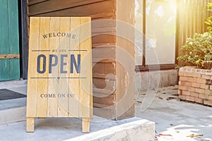 Closeup Wooden sign placed in front of the shop is labeled WELCOME Come on in We`re OPEN