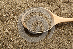 Closeup of wooden spoon with ground black pepper