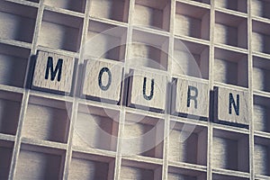 Closeup Of The Word Mourn Formed By Wooden Blocks On A Wooden Floor