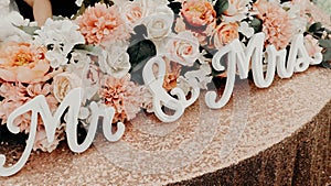 Closeup of the words "Mr. and Mrs." on a table with wedding flower arrangement