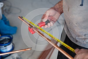 Closeup worker plumber master measures copper pipes with roulette tape, cut pipe with cutter. Concept installation, changing