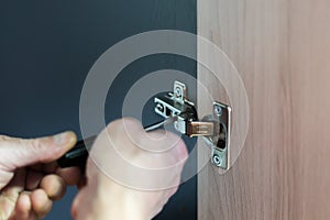 Closeup of worker`s hands fitting wardrobe hinge doors in closet