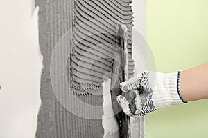 Closeup of worker spreading concrete on wall with spatula. Tile installation