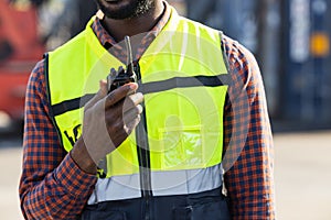 Closeup worker using ham radio for operation control in cargo port shipping