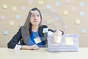 Closeup working woman are boring from pile of hard work and work paper in front of her in work concept on blurred wooden desk and