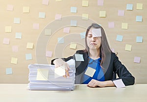 Closeup working woman are boring from pile of hard work and work paper in front of her in work concept on blurred wooden desk and