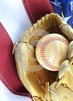 Closeup of worn baseball and mitt on a US flag background, great for America`s favorite pasttime. Vertical image.
