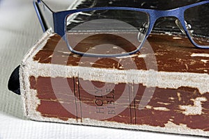 Closeup of worn leather bible with glasses resting on top