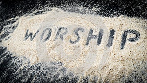 Closeup of WORSHIP text written on white sand