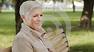 Closeup wrinkled face of 65s happy elderly woman outdoors looking aside having wide smile, dental implants and