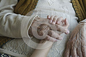 Closeup wrinkled hand holding a younger hand