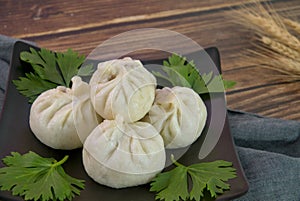 Closeup of xiaolongbao Chinese steamed bun on black plate, wood background