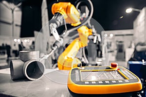 Closeup yellow arm robot welding metal pipe part in industry factory