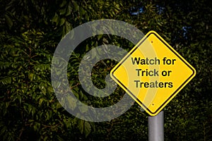 Closeup - Yellow Blank Sign against dark green foliage - Reads Watch for Trick or Treaters