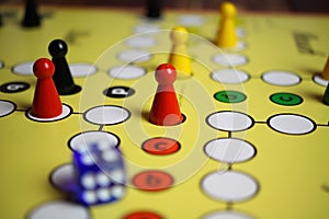 Closeup of yellow game board with colorful pieces and dice of mensch Ã¤rgere dich nicht