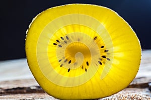 Closeup of yellow kiwi slice on wood