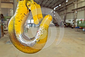 Closeup of a yellow lifting crane hook in a factory