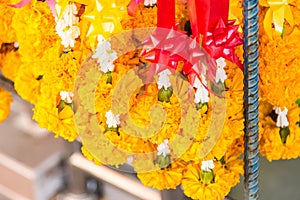 Closeup of yellow marigold flower garlands hanging at the shop in the flower market for selling. Symbol of love and respect