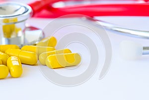 Closeup yellow pills, capsule with stethoscope background