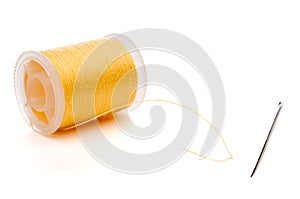 Closeup of a yellow spool of thread and a needle