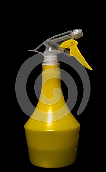 Closeup yellow spray bottle in full growth, isolated black background