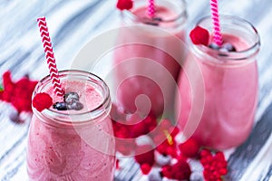 Closeup yogurt smoothie with cranberry, raspberry, blueberry on wood table in jars. Selective focus