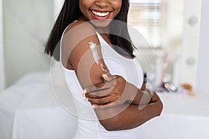 Closeup Of Young African American Woman Applying Moisturizing Body Lotion On Shoulder
