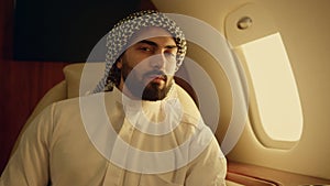 Closeup young arabian looking camera in muslim clothing. Smiling man rest at jet