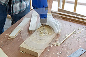 Closeup young asian carpenter drilling wooden job with electric dril